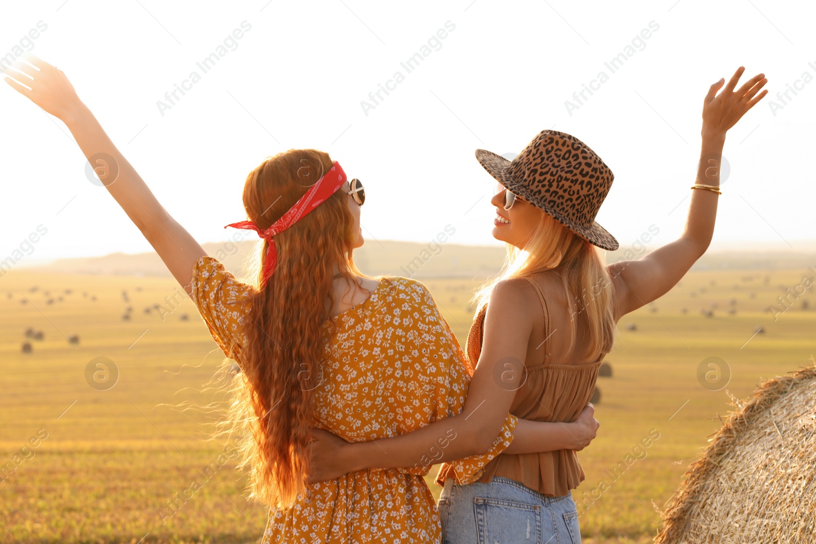 Photo of Happy hippie women in field, back view