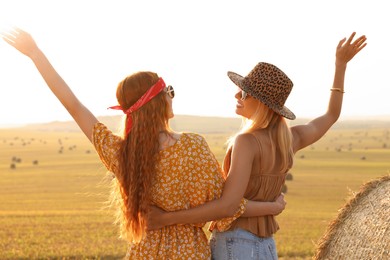 Happy hippie women in field, back view