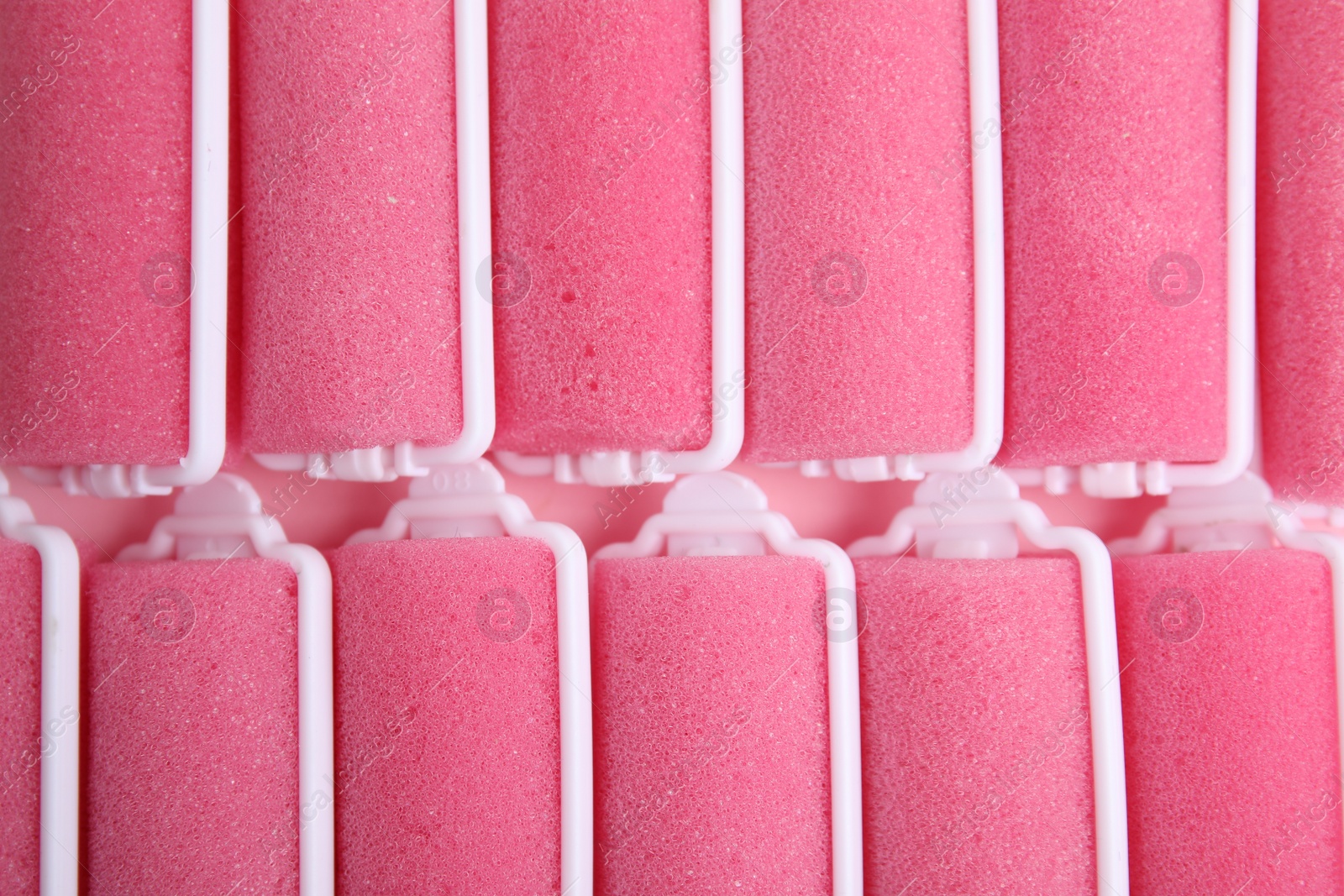 Photo of Many pink hair curlers as background, top view