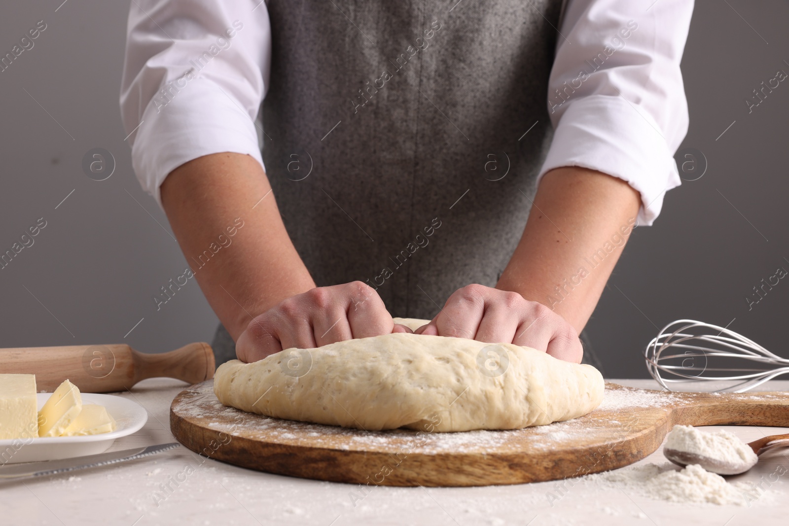 Photo of Man kneading dough at table near grey wall, closeup