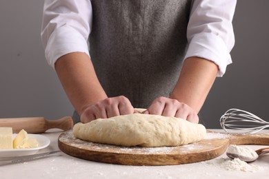 Man kneading dough at table near grey wall, closeup