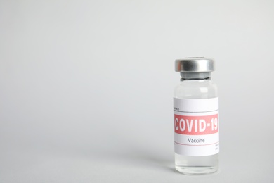 Vial with coronavirus vaccine on light background, space for text