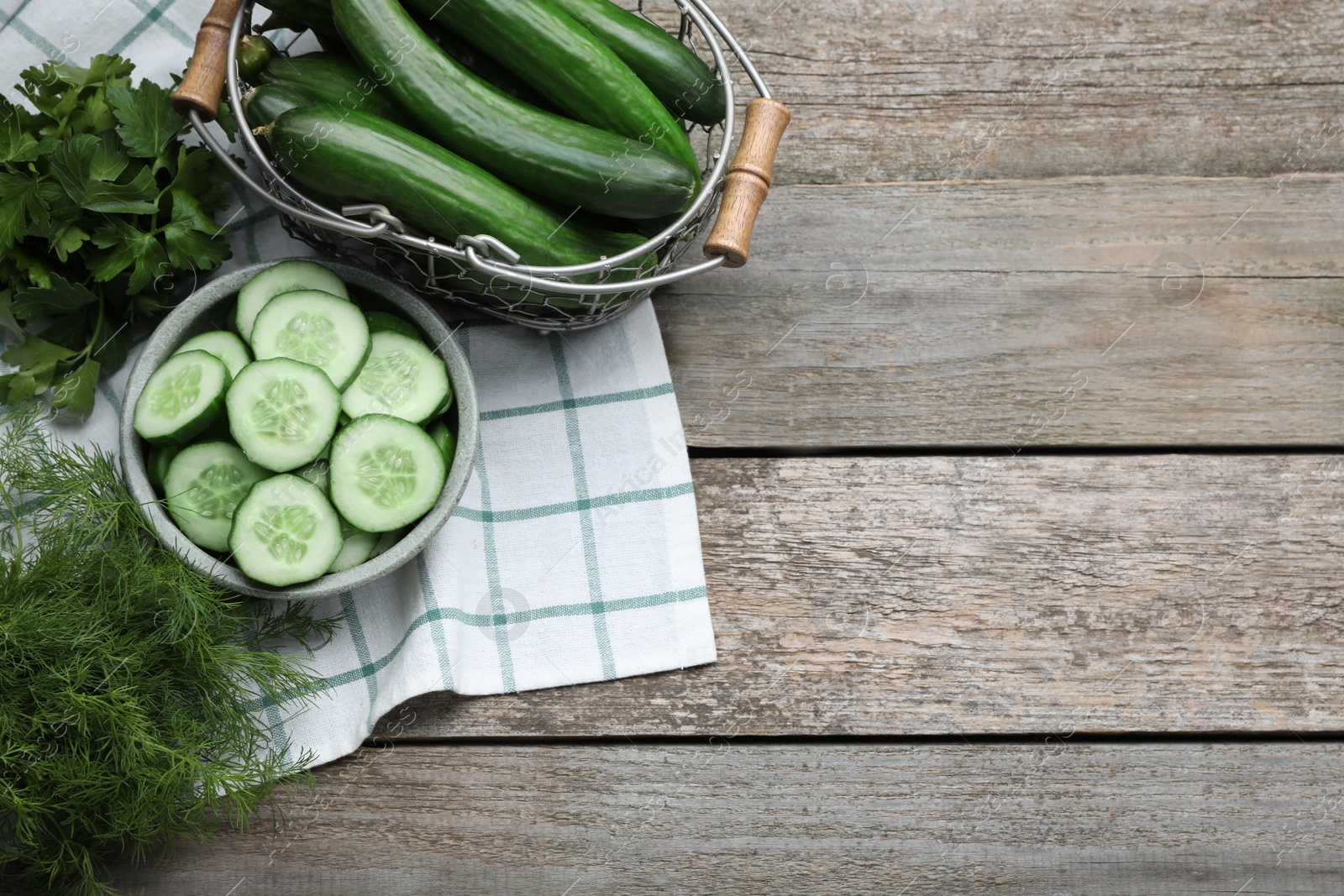 Photo of Fresh ripe cucumbers and greens on wooden table, flat lay. Space for text