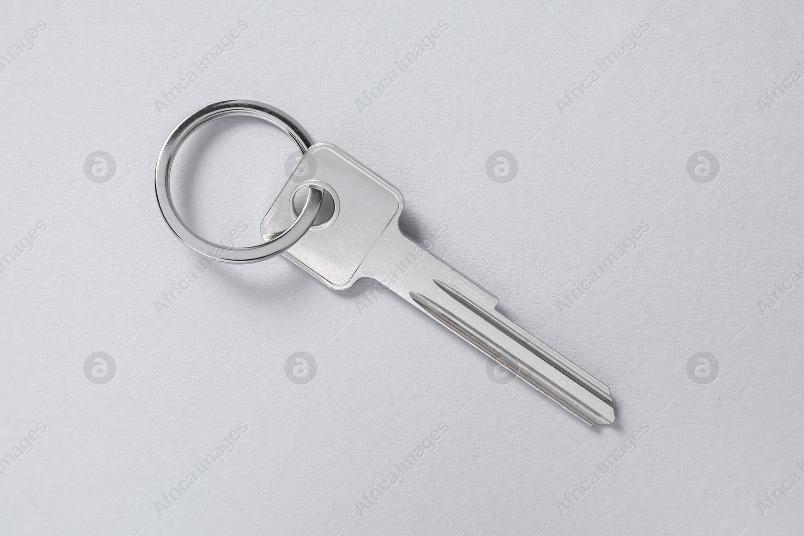 Photo of One key with ring on light background, top view