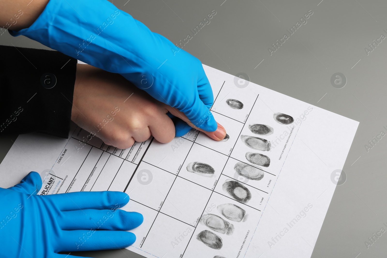 Photo of Investigator taking fingerprints of suspect at table, closeup. Criminal expertise