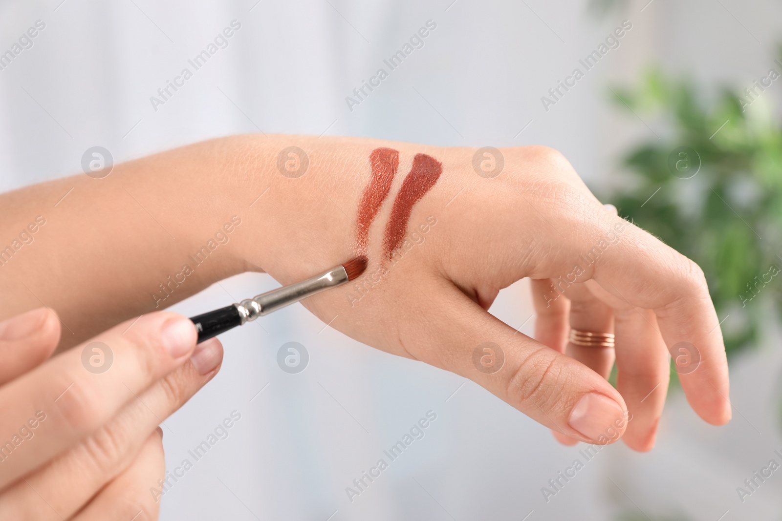 Photo of Woman testing and choosing lip gloss color on hand, closeup