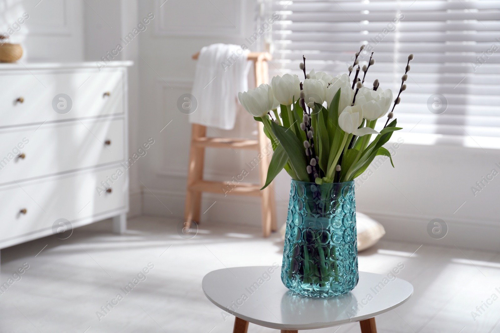 Photo of Beautiful bouquet of willow branches and tulips in vase on table indoors, space for text