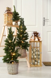 Beautiful Christmas lanterns and firs near entrance indoors