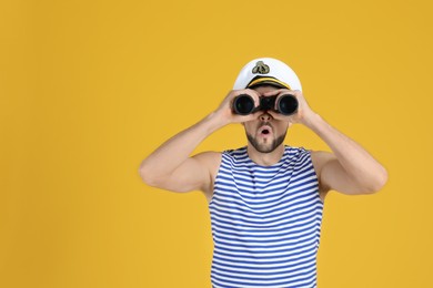 Photo of Sailor looking through binoculars on yellow background, space for text