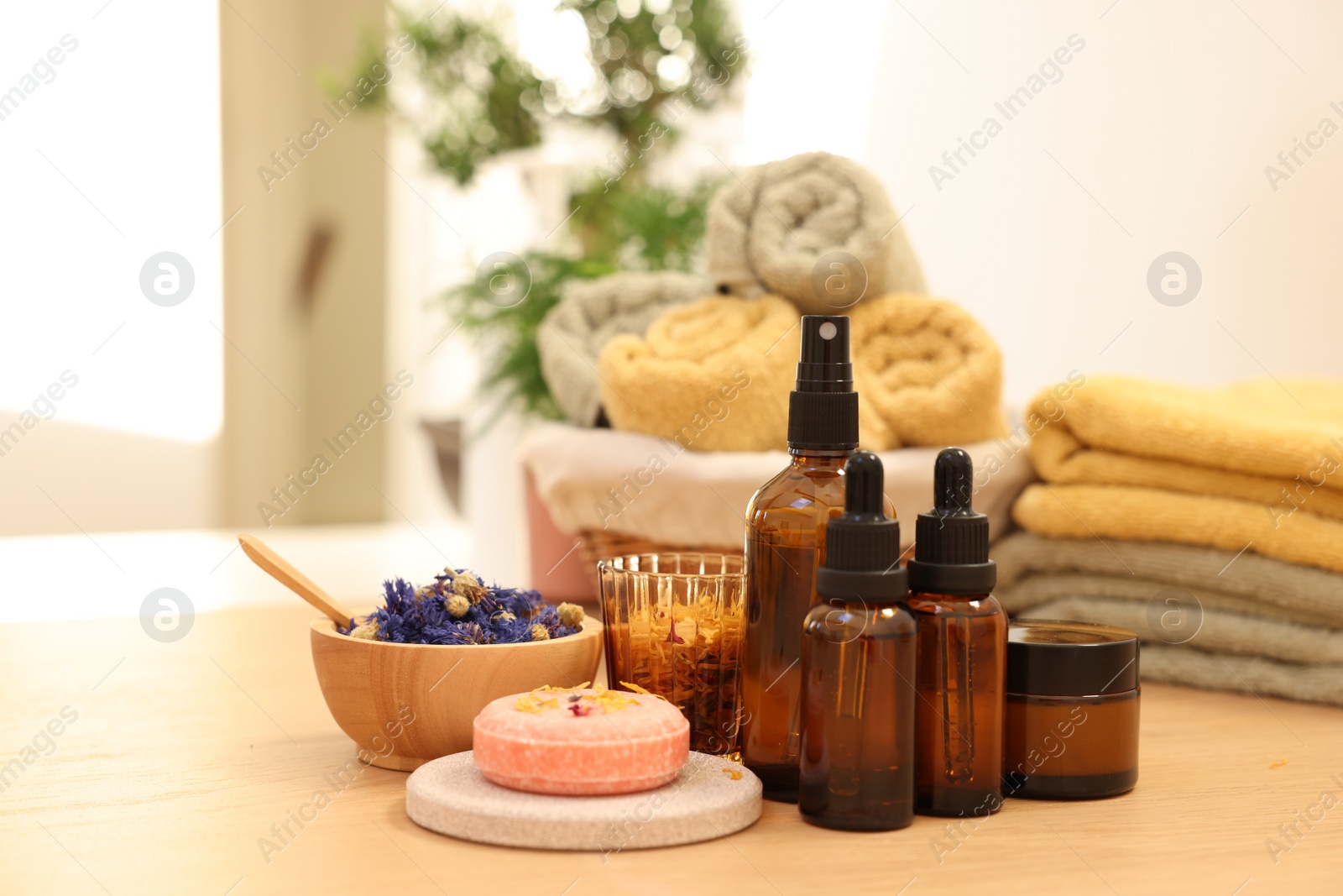 Photo of Dry flowers, soap bar, bottles of essential oils and jar with cream on wooden table indoors. Spa time