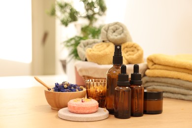 Photo of Dry flowers, soap bar, bottles of essential oils and jar with cream on wooden table indoors. Spa time