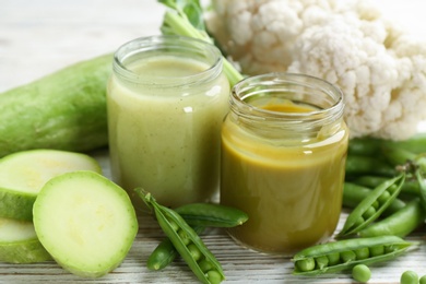 Photo of Jars with healthy baby food and ingredients on table