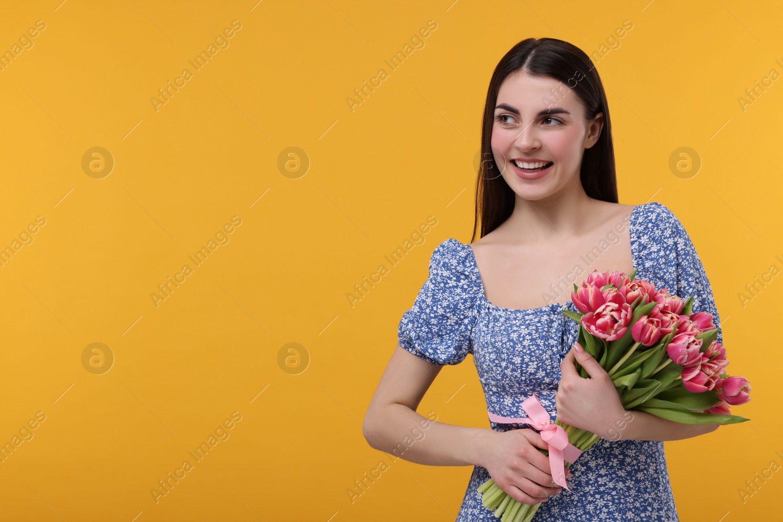 Photo of Happy young woman with beautiful bouquet on orange background. Space for text