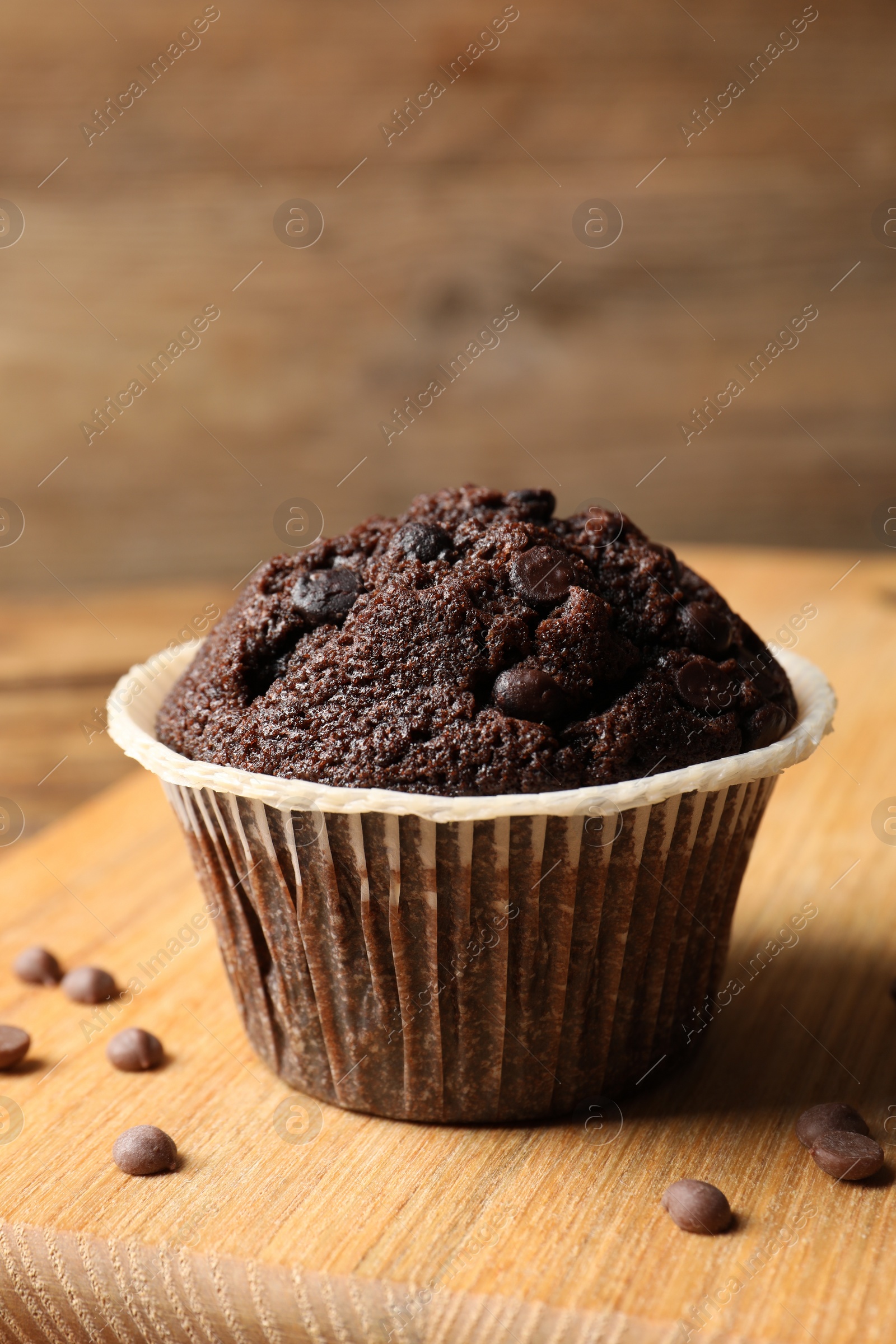 Photo of Tasty chocolate muffin on wooden board, closeup