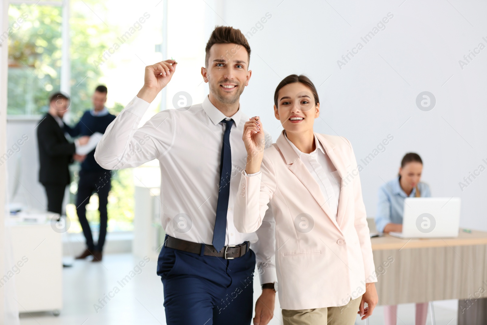 Photo of Happy young employees with darts in office