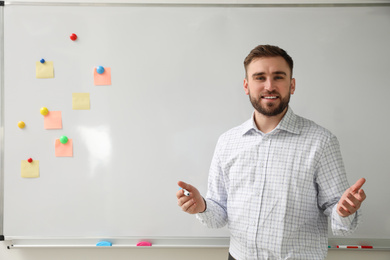 Portrait of young teacher near whiteboard in classroom