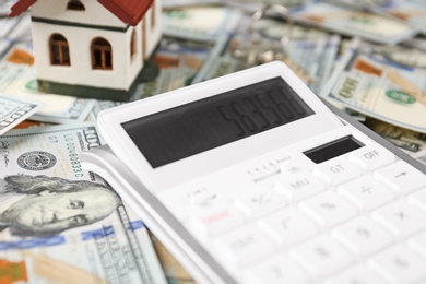 Photo of Calculator and house model on banknotes. Real estate agent concept