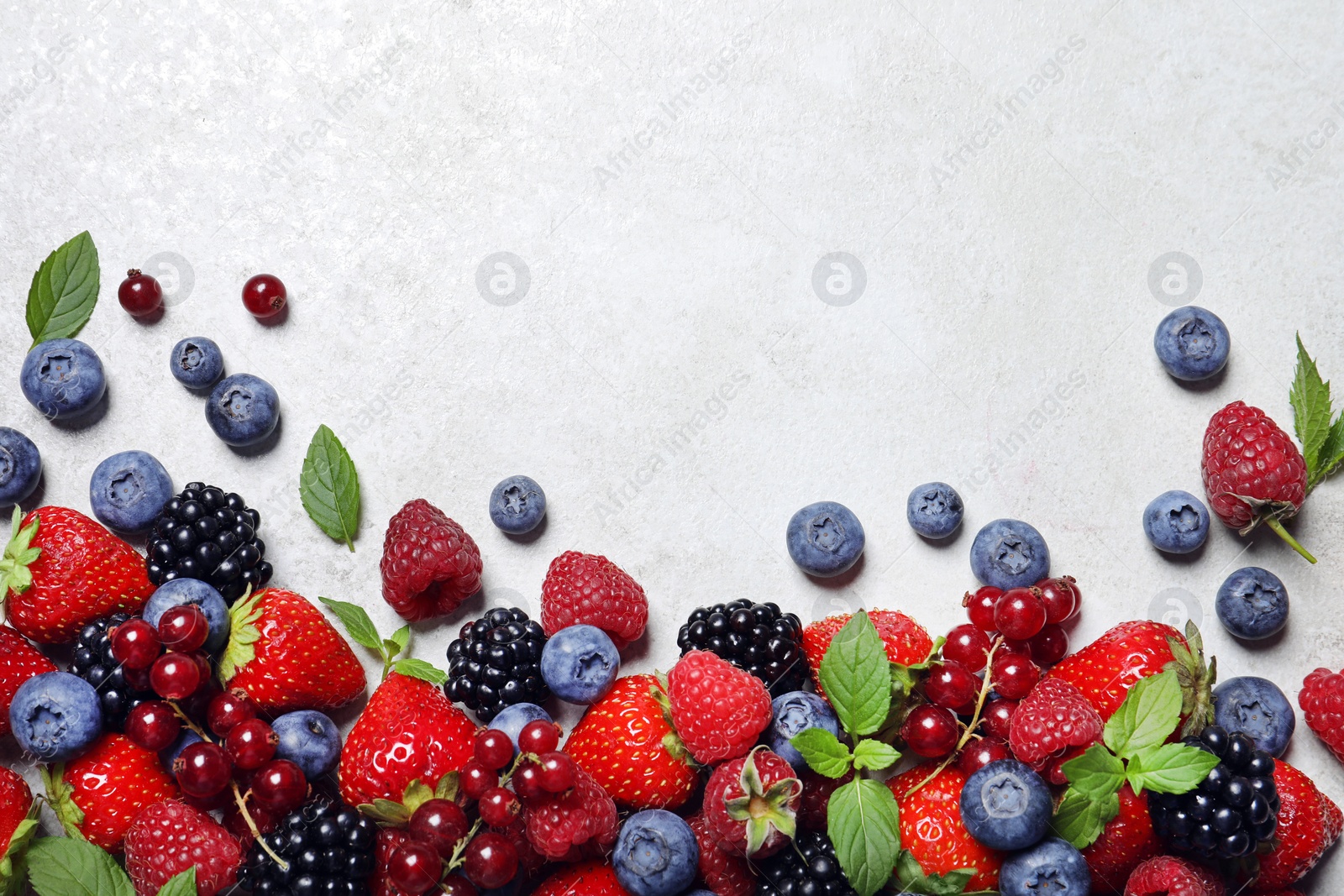 Photo of Many different fresh ripe berries on white textured table, flat lay. Space for text