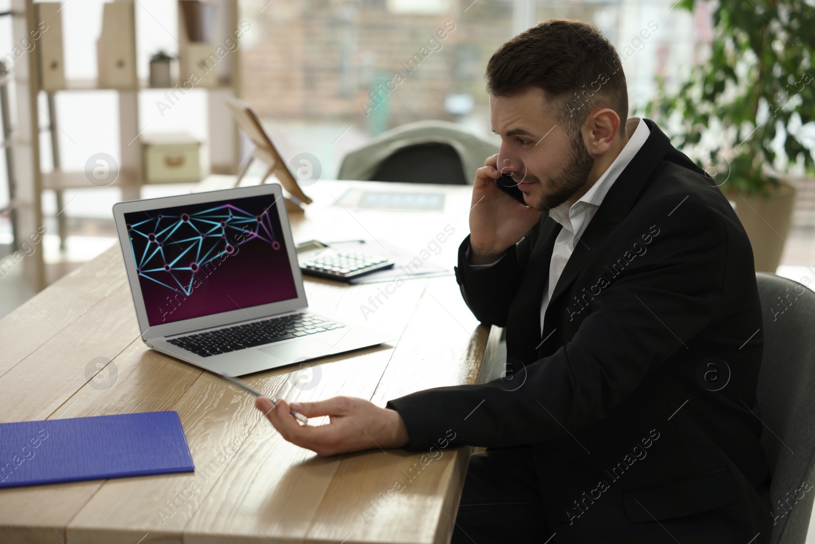 Photo of Stressed forex trader talking on phone while working in office