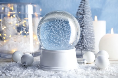 Magical empty snow globe with Christmas decorations and candles on table