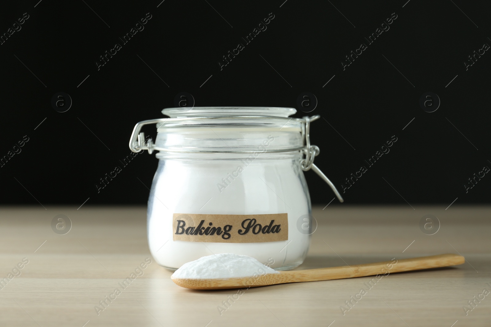 Photo of Jar and spoon with baking soda on wooden table