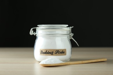 Photo of Jar and spoon with baking soda on wooden table