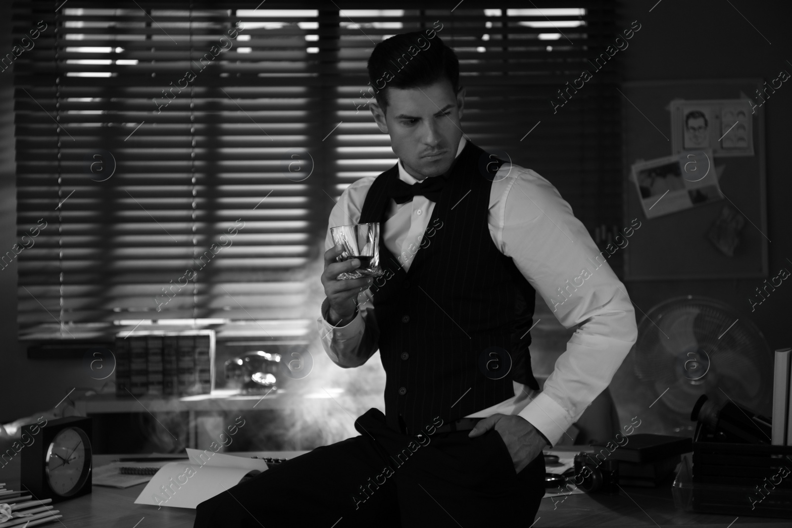Photo of Old fashioned detective with drink in office. Black and white effect