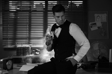 Photo of Old fashioned detective with drink in office. Black and white effect