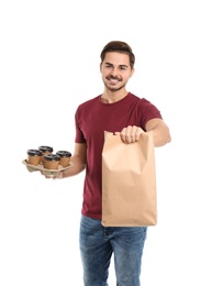 Photo of Young courier with paper bag and drinks on white background. Food delivery service