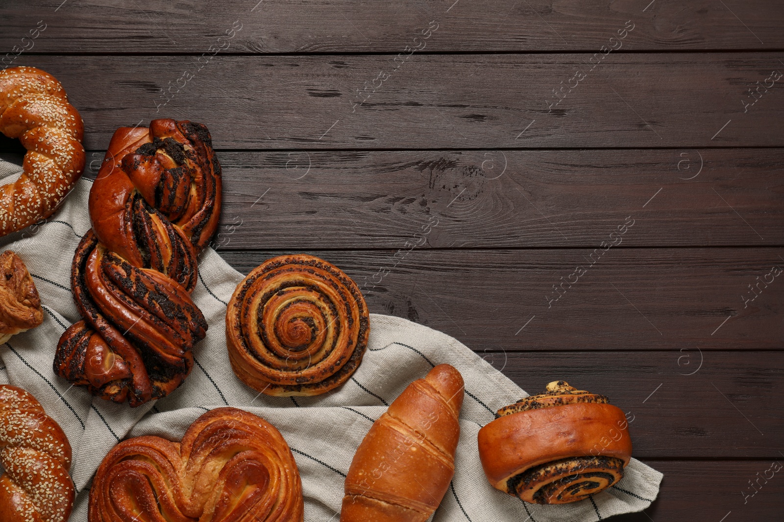 Photo of Different tasty freshly baked pastries on wooden table, flat lay. Space for text