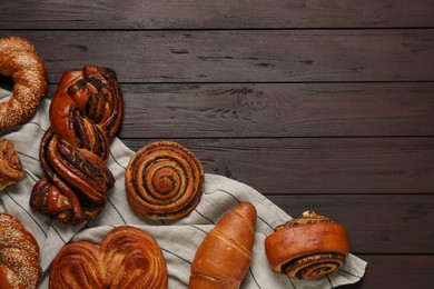 Photo of Different tasty freshly baked pastries on wooden table, flat lay. Space for text