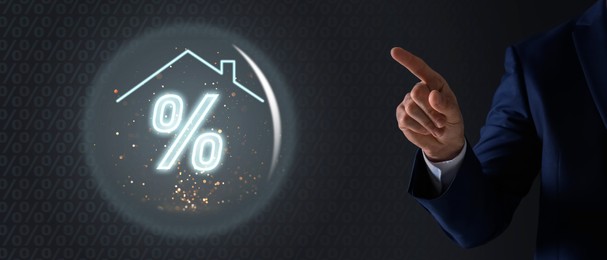 Image of Mortgage. Man pointing at sphere with percent sign and house roof on dark grey background, closeup. Banner design