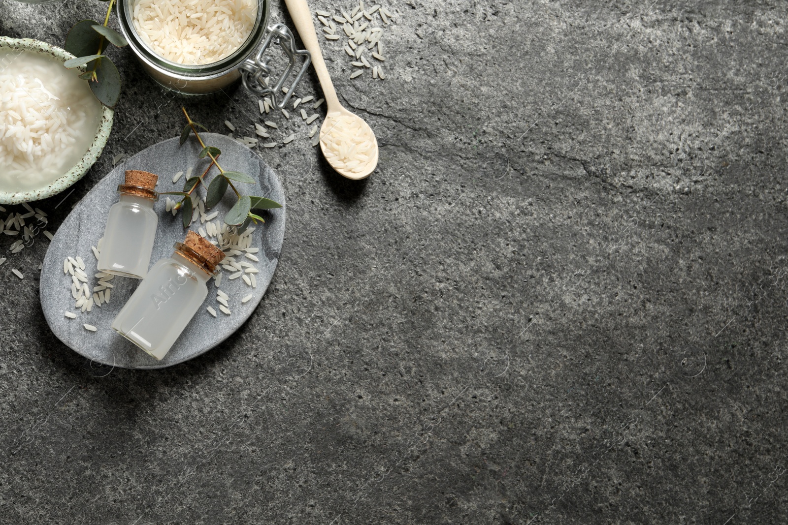 Photo of Flat lay composition with rice water on grey table. Space for text