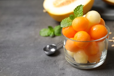 Photo of Melon balls and mint in glass on grey table, closeup. Space for text
