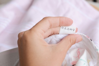 Photo of Woman holding clothing label on garment, closeup