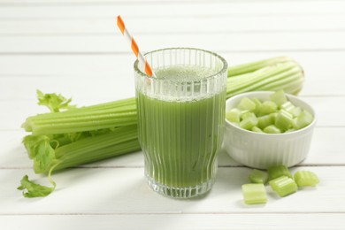 Photo of Glass of celery juice and fresh vegetables on white wooden table