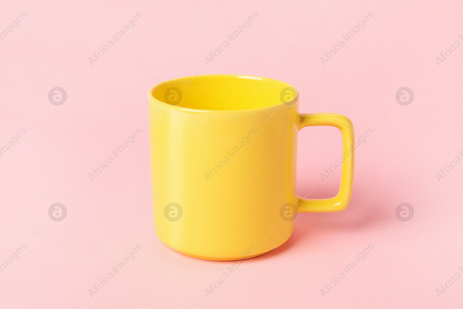 Photo of One yellow ceramic mug on pink background