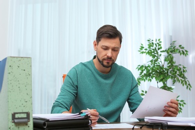 Photo of Man working with documents at table in office