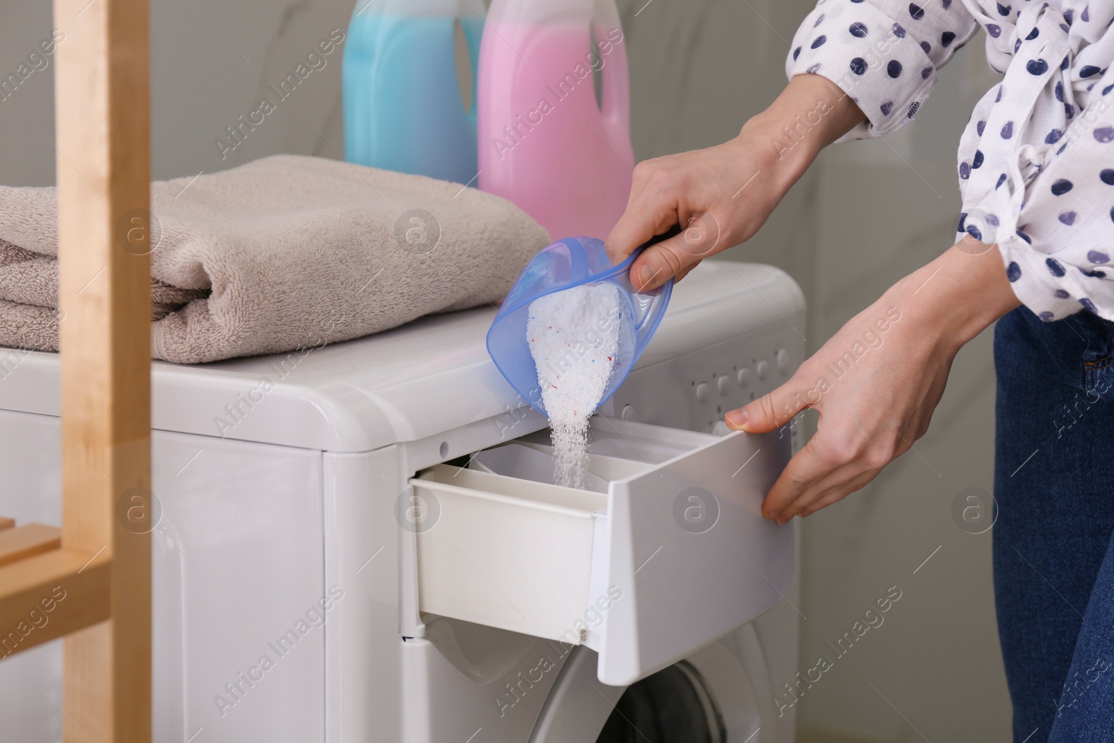 Photo of Woman pouring laundry detergent into washing machine drawer in bathroom, closeup