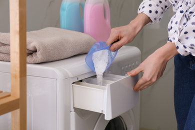 Woman pouring laundry detergent into washing machine drawer in bathroom, closeup