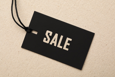 Image of Tag with text SALE on color fabric background, top view. Black Friday 