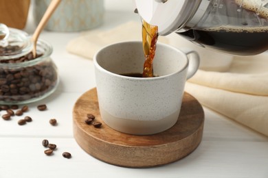 Pouring coffee into cup at white wooden table, closeup