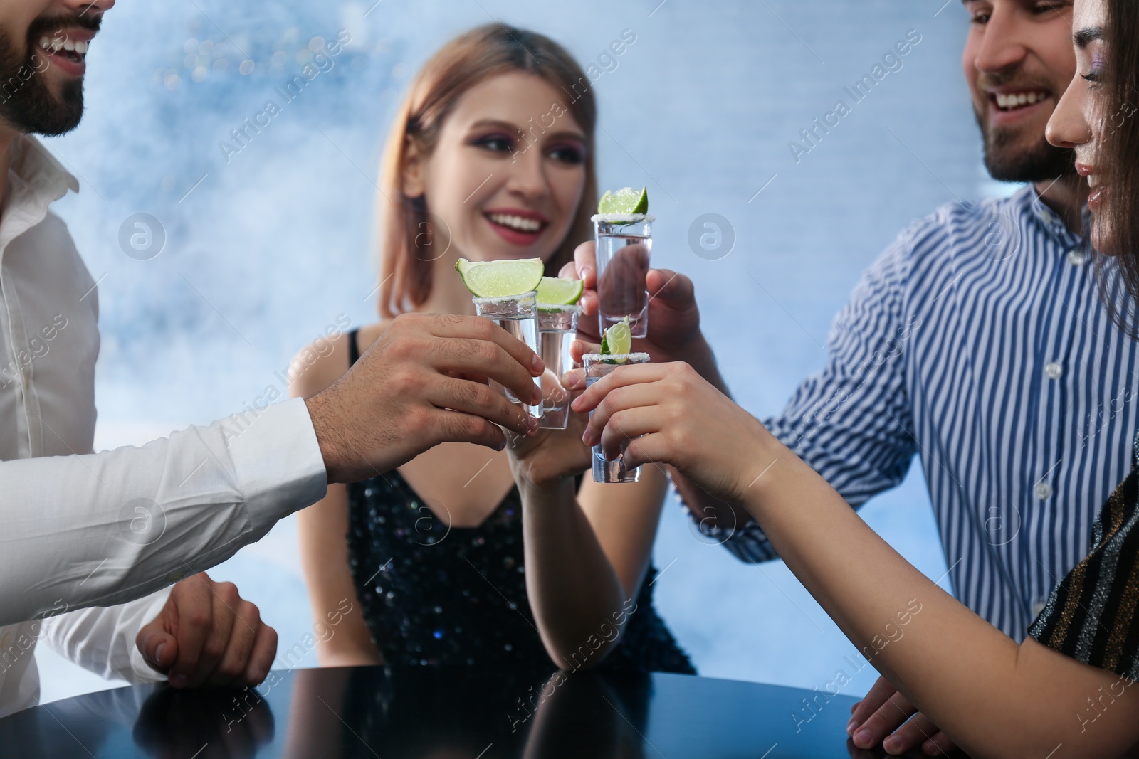 Photo of Young people toasting with Mexican Tequila shots at table in bar