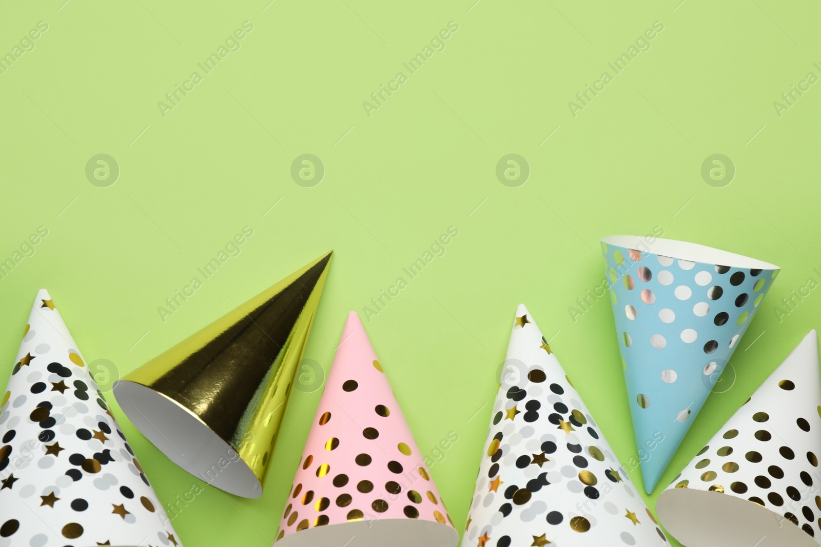 Photo of Bright party hats on light green background, flat lay. Space for text
