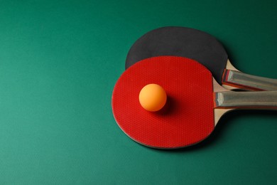 Photo of Ping pong ball and rackets on green background. Space for text