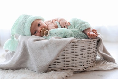 Photo of Cute newborn baby lying on plaid in basket at home