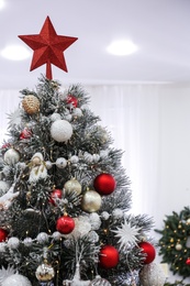 Beautiful Christmas tree with star topper in decorated room