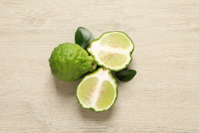 Photo of Whole and cut ripe bergamot fruits with green leaves on white wooden table, flat lay