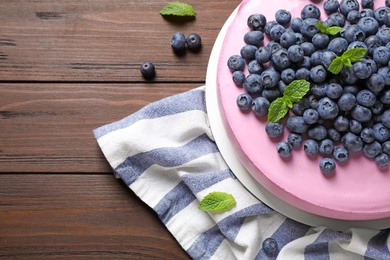 Photo of Tasty blueberry cake and napkin on wooden table, flat lay. Space for text