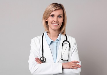 Photo of Smiling doctor with crossed arms on grey background